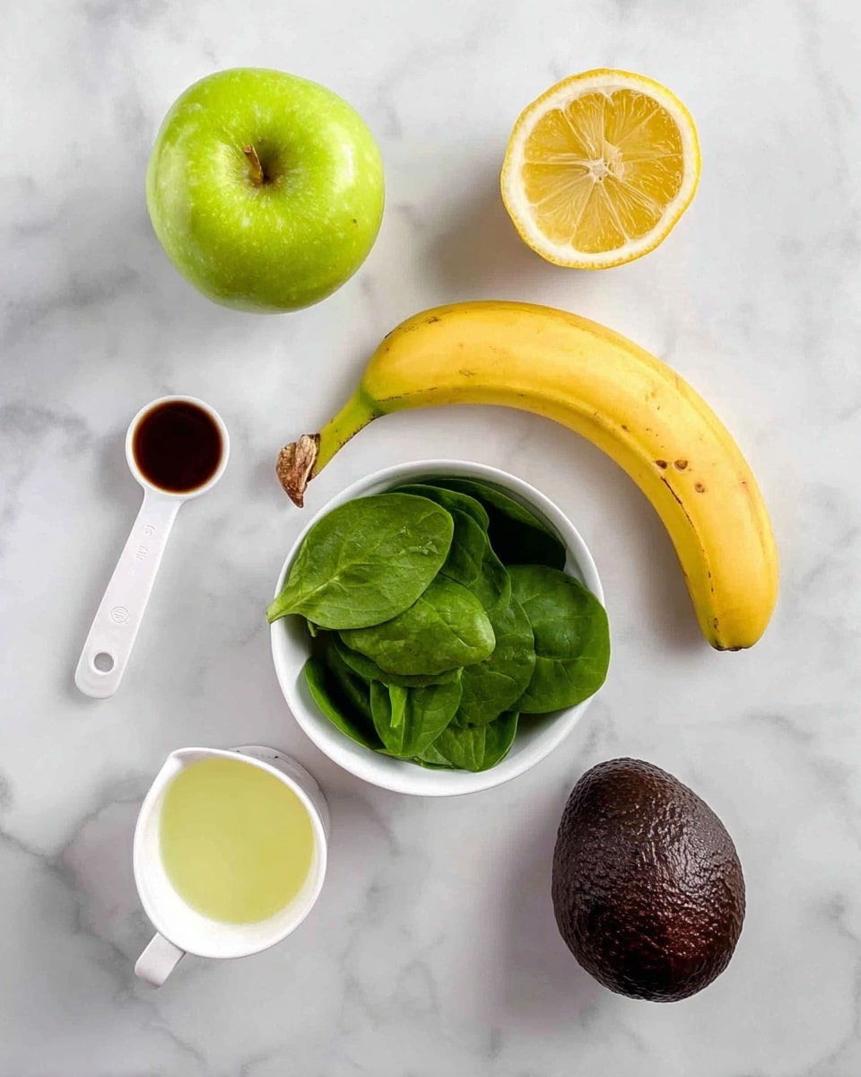 The image shows six ingredients arranged neatly on a white marbled surface. At the top left is a green apple with a shiny, smooth texture. To its right is a half lemon showing its bright yellow juicy inside. Below the apple is a white measuring spoon containing a small amount of dark liquid. A curved yellow banana with a few brown spots is placed in the center, just above a white bowl filled with fresh, bright green spinach leaves. To the right of the bowl is a whole dark brown avocado with a bumpy skin. At the bottom left corner is a white measuring cup with a light yellow liquid inside. Photo taken with an iphone --ar 4:5 --v 7