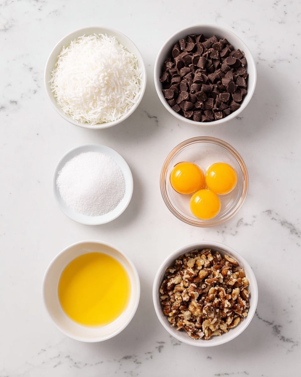 The image shows five small white bowls arranged on a white marbled surface. The top left bowl is filled with finely shredded white coconut, while the top right bowl contains dark brown chocolate chips with a mix of large and small pieces. Below the chocolate chips, there is a clear glass bowl holding two bright yellow egg yolks. In the center bottom left, a white bowl contains a smooth, golden-yellow liquid, likely melted butter. To the bottom right, another white bowl is filled with coarse chopped brown nuts. In the middle between all bowls, a small shallow white bowl holds white granulated sugar. The image is well-lit, clean, and minimalistic, photo taken with an iphone --ar 4:5 --v 7
