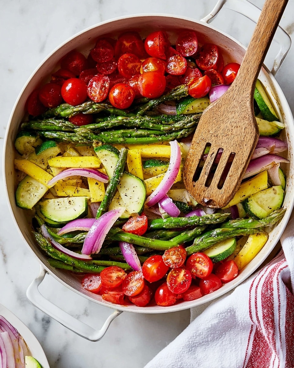 A white pan filled with three layers of colorful vegetables: the bottom layer shows green asparagus stalks, yellow squash slices, and green zucchini slices mixed with thin slices of purple onion; the middle layer features bright red halved cherry tomatoes scattered around; the top layer is lightly sprinkled with black pepper and minced garlic bits. A wooden spatula with a slotted design rests on top of the vegetables. The pan is placed on a white marbled surface with a white cloth having a red stripe partially visible on the right side. photo taken with an iphone --ar 4:5 --v 7