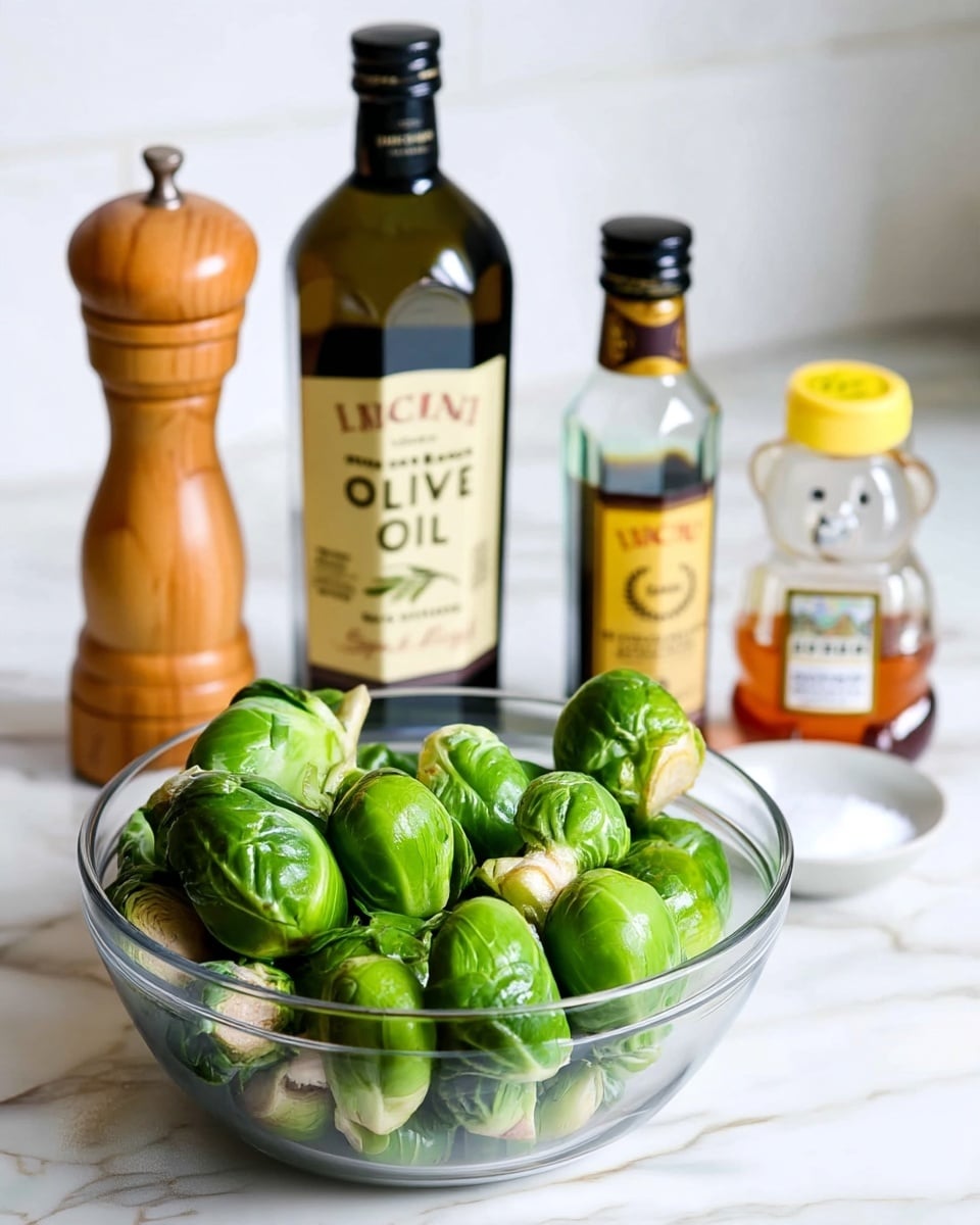 A clear glass bowl sits on a white marbled surface filled with fresh green Brussels sprouts showing their tight, leafy texture. Behind the bowl, there is a tall dark green bottle of olive oil with a cream label and black cap, next to a shorter clear bottle of balsamic vinegar that has a dark brown liquid and a yellow label with a black cap. To the right, a small white bowl holds coarse salt, and beside it is a cute honey bottle shaped like a bear with a yellow cap and honey inside. On the left side of the bowl, a wooden pepper grinder with a smooth, round top stands tall. The background is white tile. photo taken with an iphone --ar 4:5 --v 7